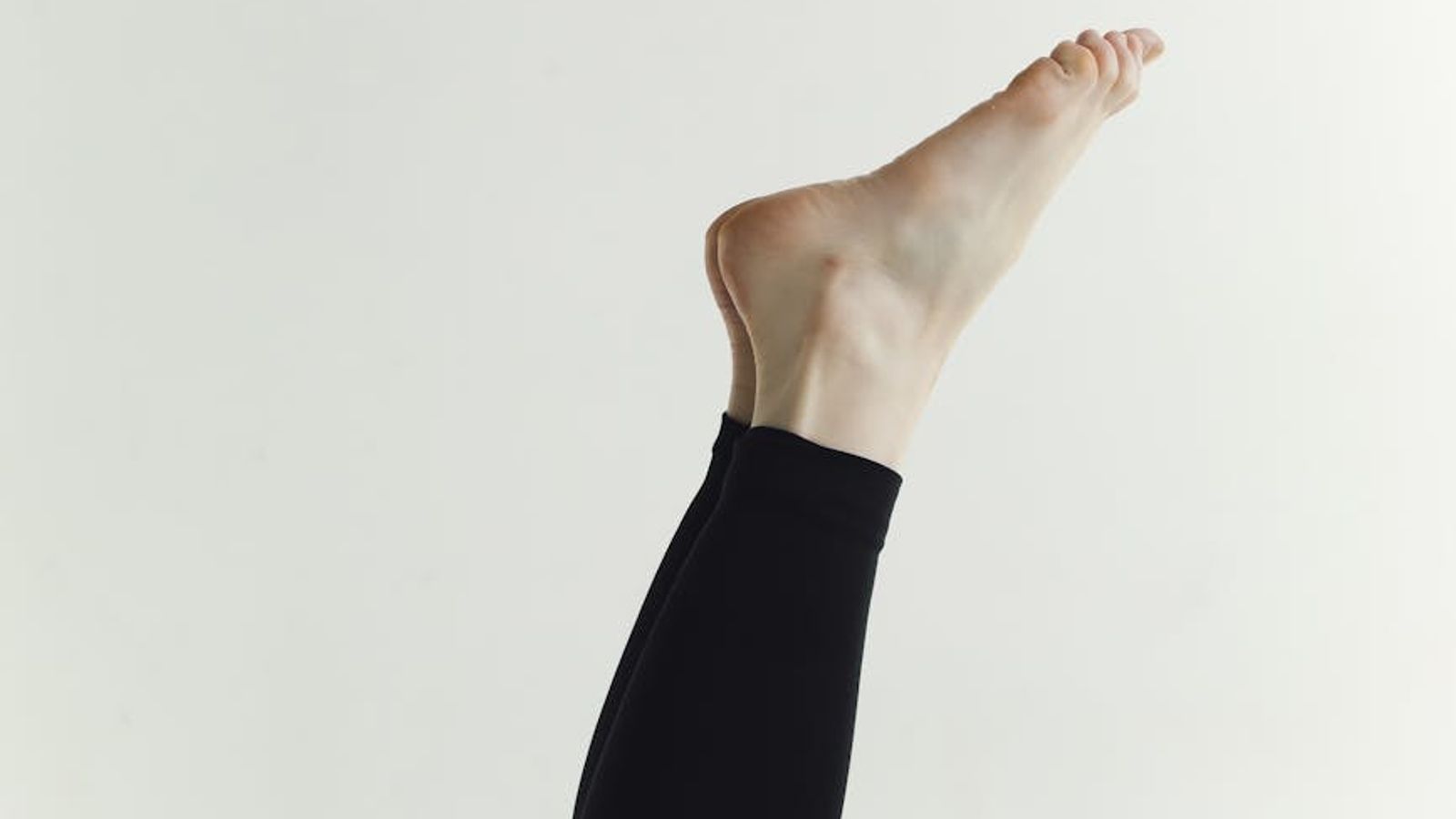 Person in a dynamic but calm movement pose in a bright, minimalist studio.